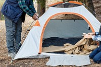 Happy elderly couple setting up a tent in the forest