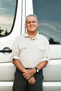 Senior man standing by the camper van