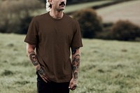 Attractive man in brown t-shirt with design space standing in countryside