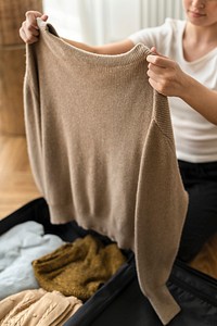 Wife packing her winter clothes in a luggage for a trip