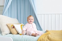 Cute baby girl sitting on her bed