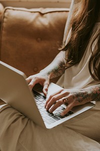 Tattooed woman work form home on a sofa