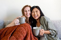 Female couple cuddling on sofa in morning