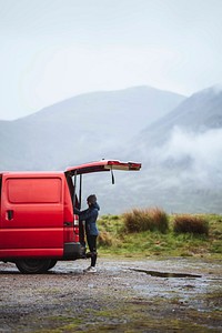 Woman standing by the red van in the highlands