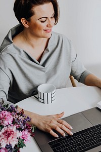 Cheerful woman reading a book by her laptop