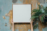 Woman holding a blank frame against a grungy wall