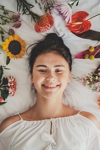 Beautiful young girl lying in a bed with flowers