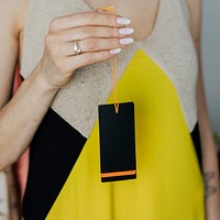 Woman in a yellow dress holding a black cloth brand tag