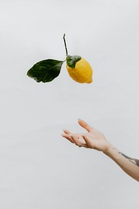 Tattooed hand throwing a lemon up in the air