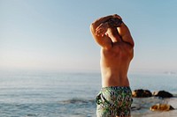 Tattooed man stretching his arm at the beach