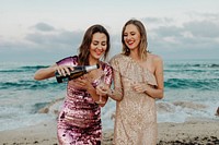 Women filling up a glass of champagne at the beach