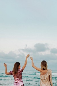 Women dancing with glasses of champagne at the beach