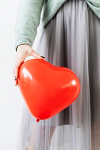 Woman in a gray chiffon skirt showing a red balloon