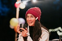 Woman keeping warm with hot chocolate, a beanie, and a shawl 