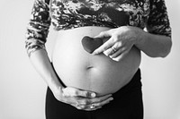 Pregnant woman holding a heart in front of her baby bump