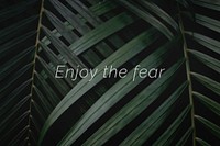 Enjoy the fear quote on a palm leaves background