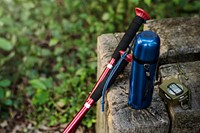 Trekking pole, water bottle and compass isolated on a rock outdoor