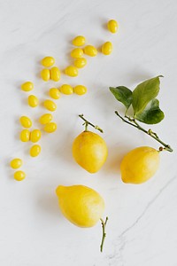 Fresh lemons and limoncello candy on white marble table flatlay