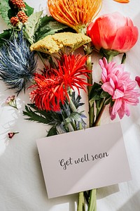 Bouquet of colorful flowers on a white bed sheet with a card