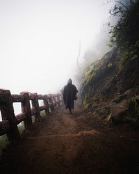 Man in a raincoat walking up a steep dirt road