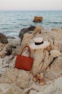 Straw hat and a woven bag on a rocky beach