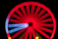 Blurry red neon Ferris wheel in a carnival at night