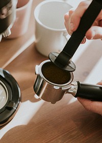 Barista pressing ground coffee in a coffee machine filter