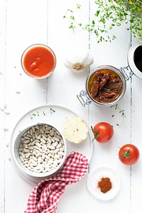 Raw white beans in a bowl by sun-dried tomatoes