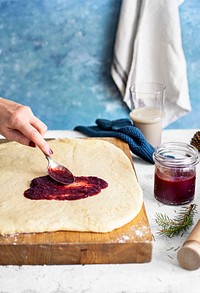Woman spreading cherry jam on fresh dough