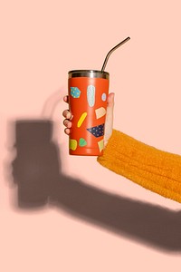 Woman holding an orange tumbler mockup against a pink background