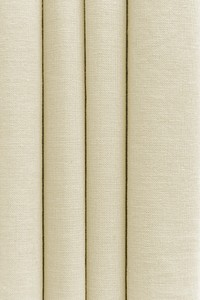 Stack of folded beige woven fabric textured background