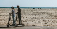 Couple riding a scooter by the beach