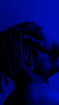 Black man covering his face on a blue background