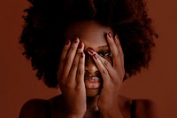 Black woman with afro hair covering her face with hands