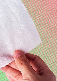 Hand getting toilet paper on pink and green background