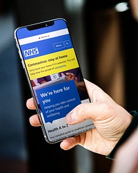 Man reading coronavirus updates from a mobile phone mockup with editorial graphic from <a href="https://www.nhs.uk/" target="_blank">https://www.nhs.uk</a> accessed on April 8th 2020. LOS ANGELES, USA - JUNE 28, 2019