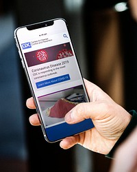 Man reading coronavirus updates from a mobile phone mockup with editorial graphic from <a href="https://www.cdc.gov/" target="_blank">https://www.cdc.gov</a> accessed on April 8th 2020. LOS ANGELES, USA - JUNE 28, 2019