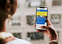 Woman reading coronavirus updates from a mobile phone mockup with editorial graphic from <a href="https://www.nhs.uk/" target="_blank">https://www.nhs.uk</a> accessed on April 8th 2020. LOS ANGELES, USA &ndash;APRIL 9, 2019