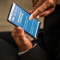 Businessman reading coronavirus information from a phone mockup with editorial graphic from <a href="https://www.coronavirus.gov/">https://www.coronavirus.gov/</a> accessed on April 8th 2020. BANGKOK, THAILAND - MARCH 28, 2018