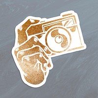 Shimmering golden analog camera sticker overlay on a gray background 