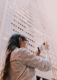Woman using smartphone taking a picture in city