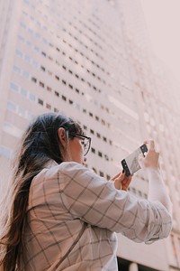 Woman using smartphone taking a picture in city