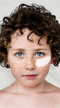 Curly haired boy with freckles and white paint on his cheek