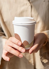 Abstract patterned disposable coffee cup in woman&rsquo;s hands