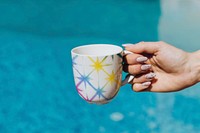 Hand holding a coffee cup in colorful tie dye pattern