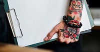 Tattooed hand holding a blank paper clipboard website banner template