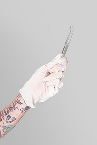 Tattooed hand in a white glove holding a curved tweezers
