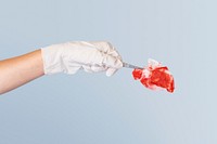 Gloved hand using tweezers to hold a red gauze