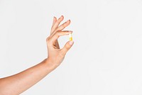 Hand holding a white and yellow pill