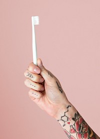 Tattooed hand holding a toothbrush